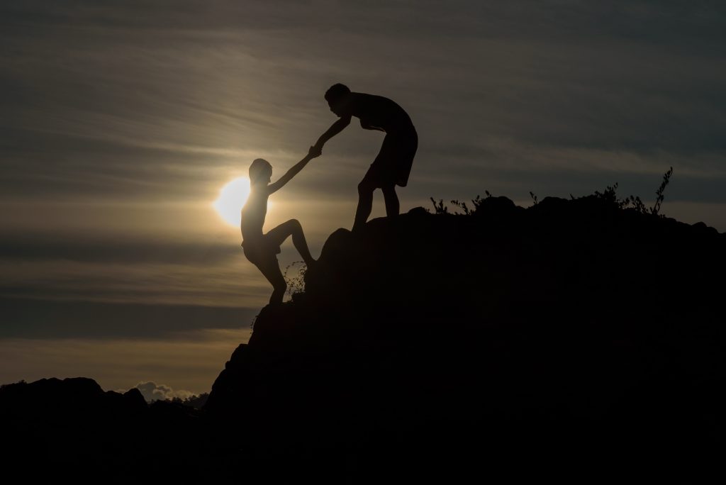 Silhouette of two boys helped pull together climbing