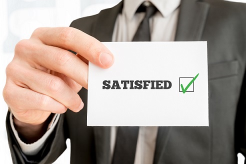 Customer feedback - Satisfied - concept with a businessman holding up a card with a ticked check box from a survey or feedback report and the word Satisfied, close up of his hand.